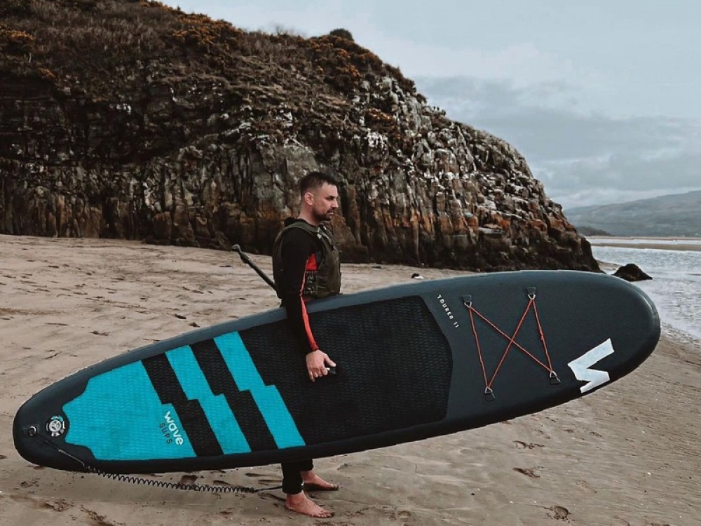 Man holding paddle board at the coast