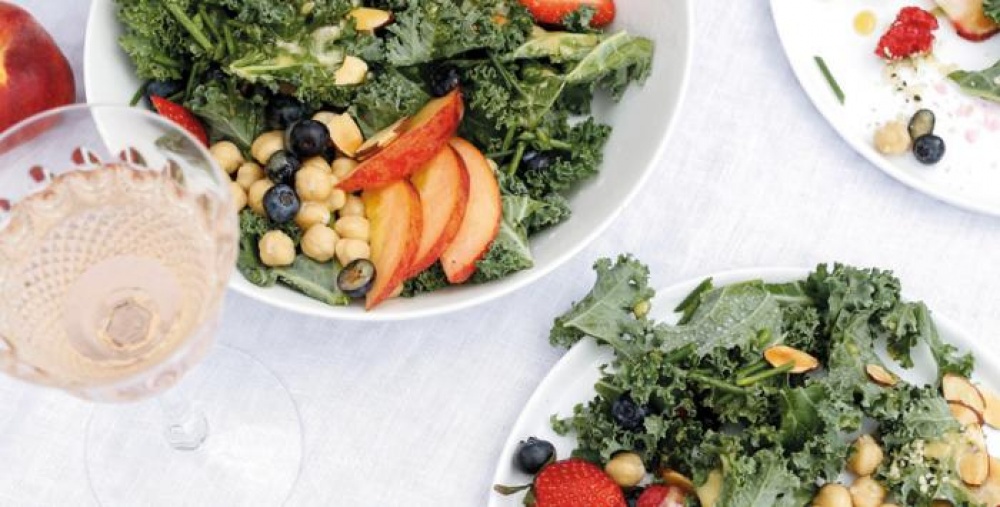 Leafy greens with apples, chickpeas in two bowls with a glass of whit wine on the table