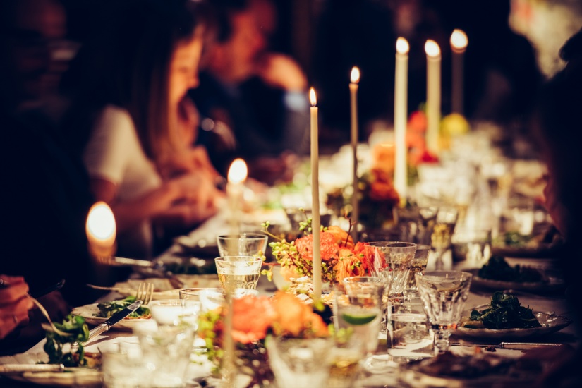 Candles on a dinner table with wine glasses and crockery