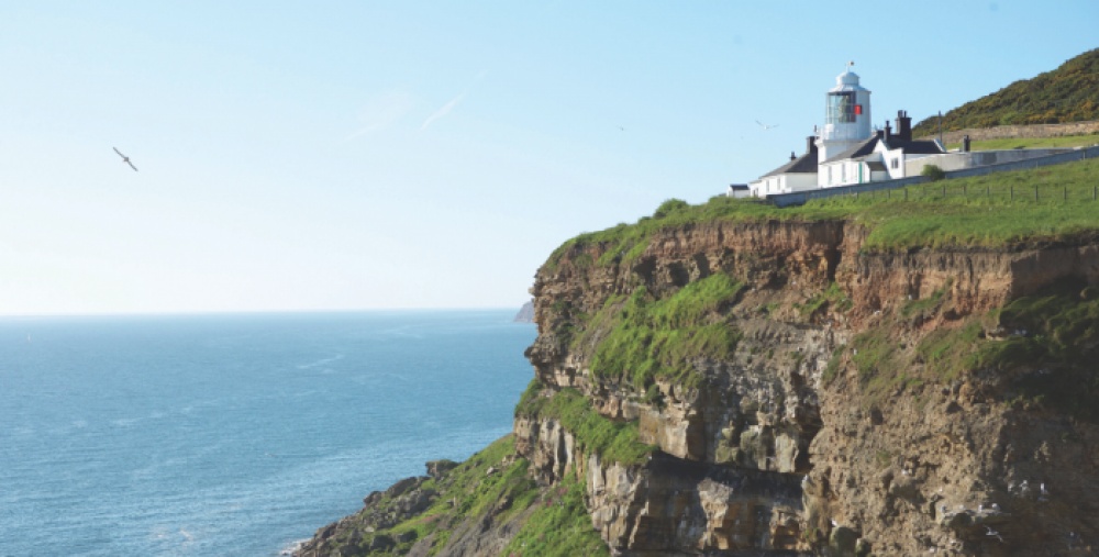 The sea and a cliff with a white lighthouse on it