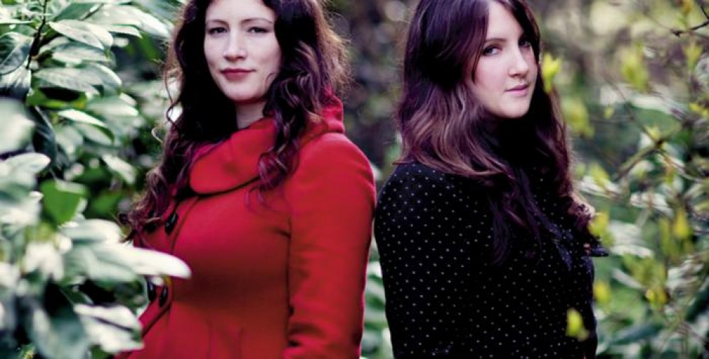 Two brunette women one with a red coat on and the other with a black jacket on from the band The Unthanks