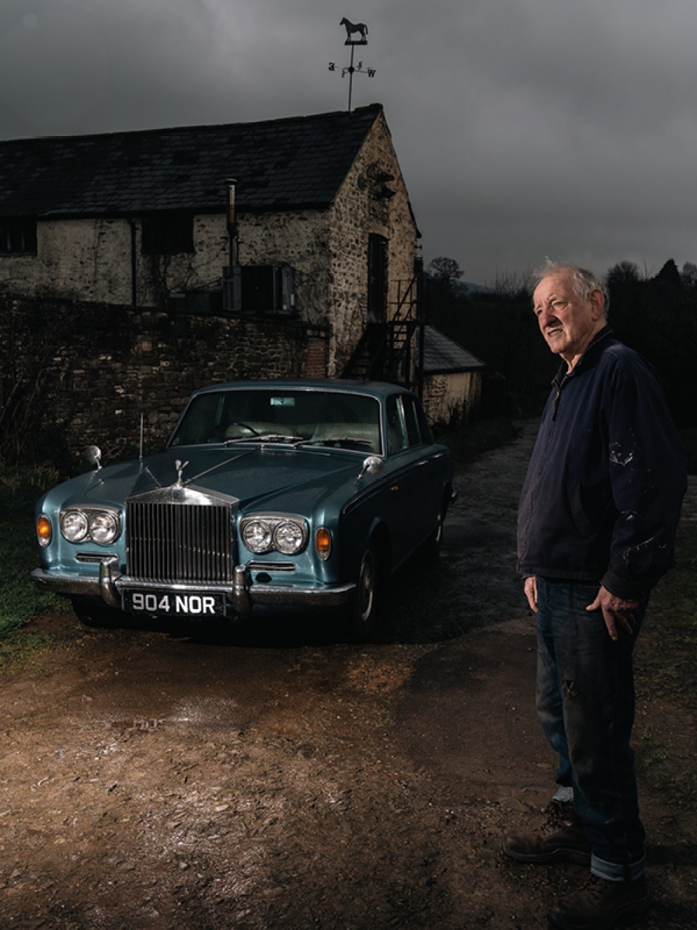 Rolls Royce in from of building with a weather vane with a man in the foreground