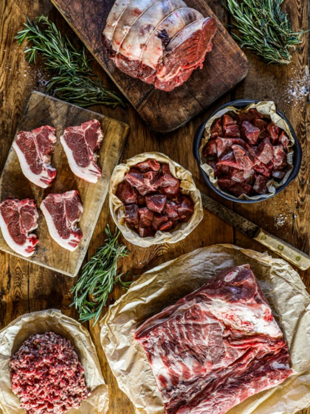 different cuts of raw meat with Rosemary laid between