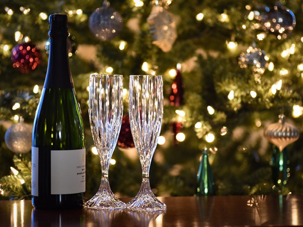 Bottle of fizz and 2 glasses in front of a dressed Christmas tree