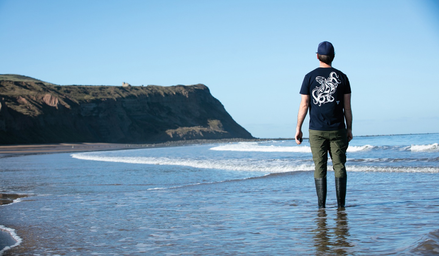 Richard standing in the water looking out towards the sea and cliffs