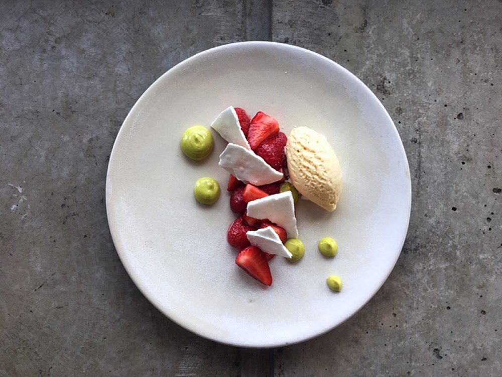 a plate of food with chopped strawberries, ice cream, and pistachio cream