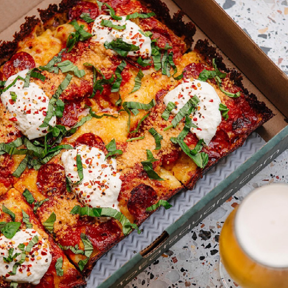 Pizza with meat and eggs with a beer