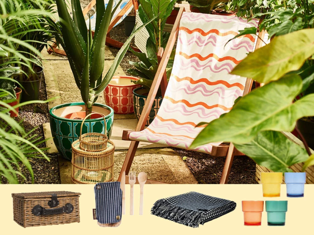 picnic basket, cheese board, flowers, book and hat on a throw
