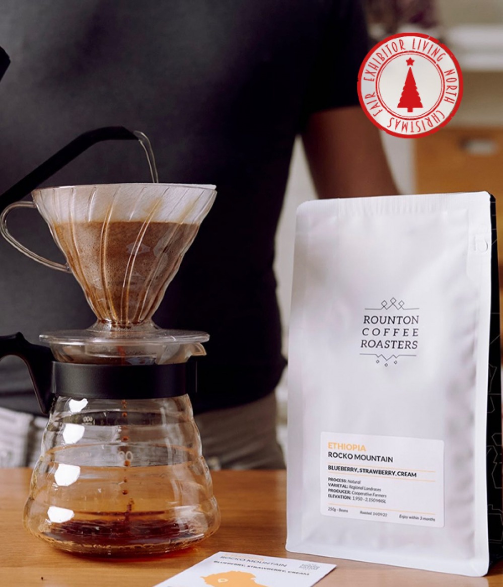 bag of coffee and a man pouring water into cafetière