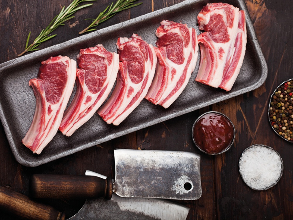 Raw chops on a tray with a meat cleaver and pots of seasoning