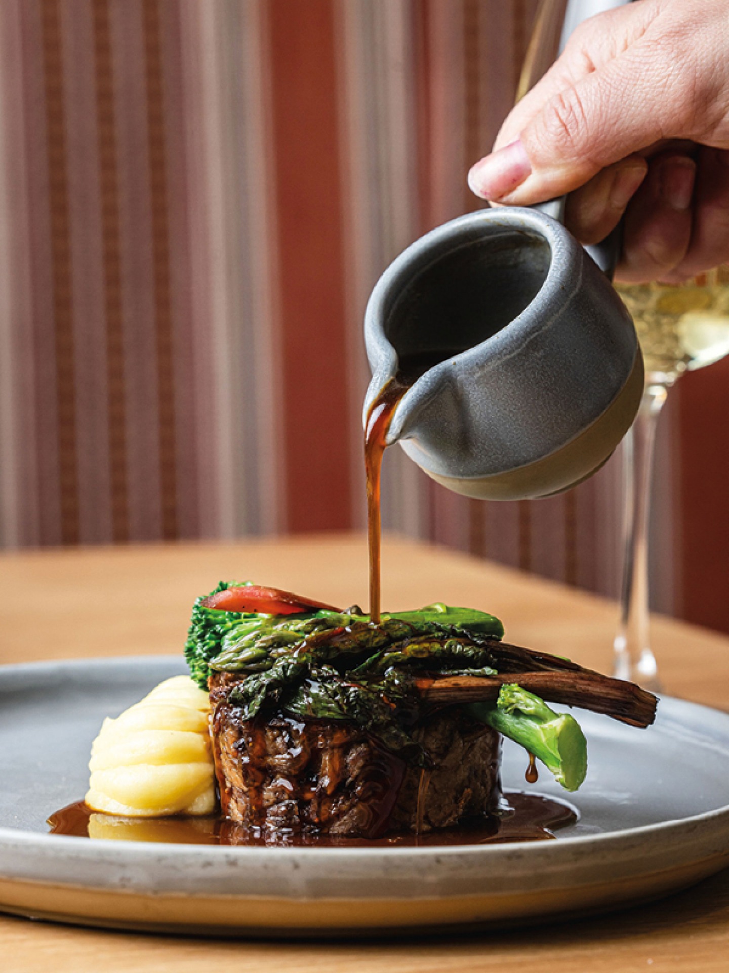 Gravy being poured over meat and vegetable