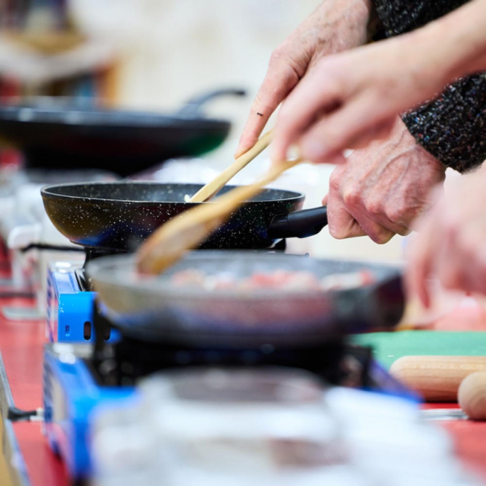 Food being stirred in frying pans on mini stoves