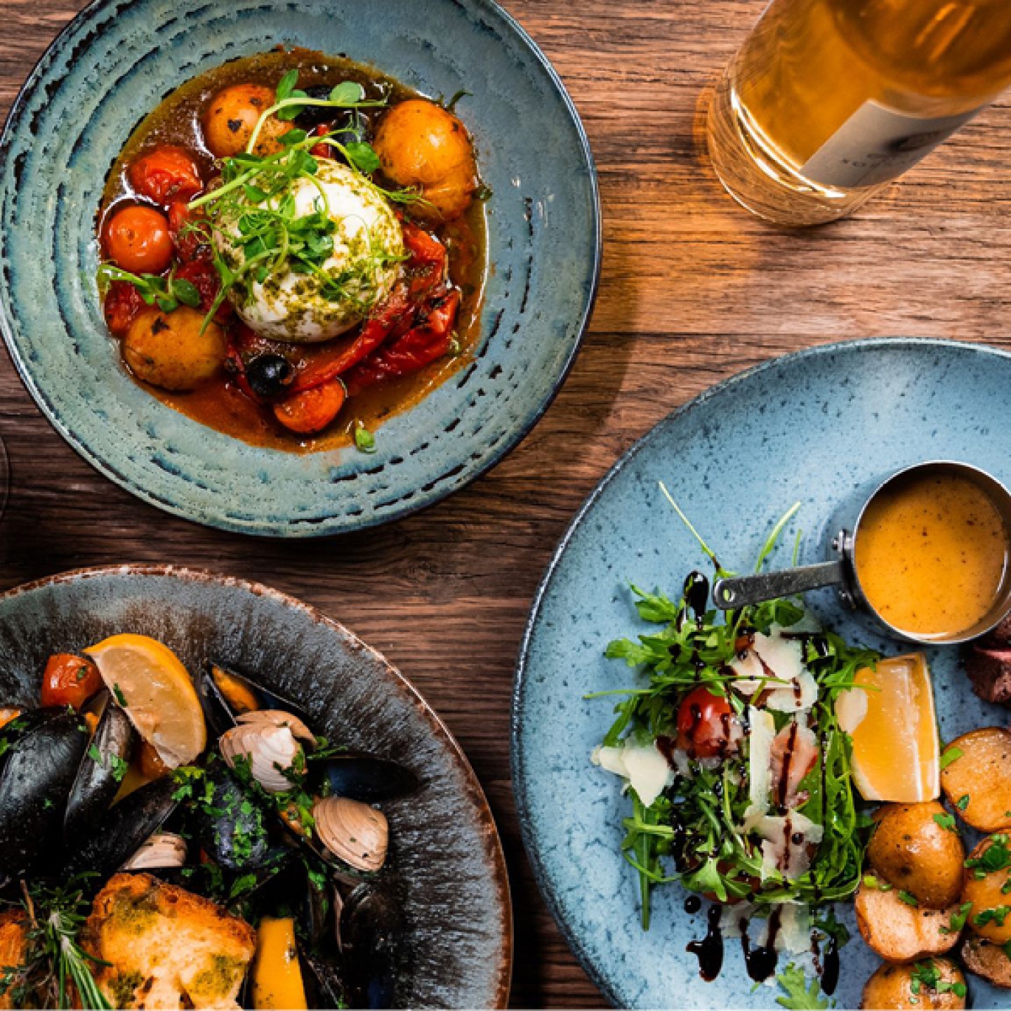 Bowls of Italian food including mussels, burrata in tomato and oil and seasoned potatoes