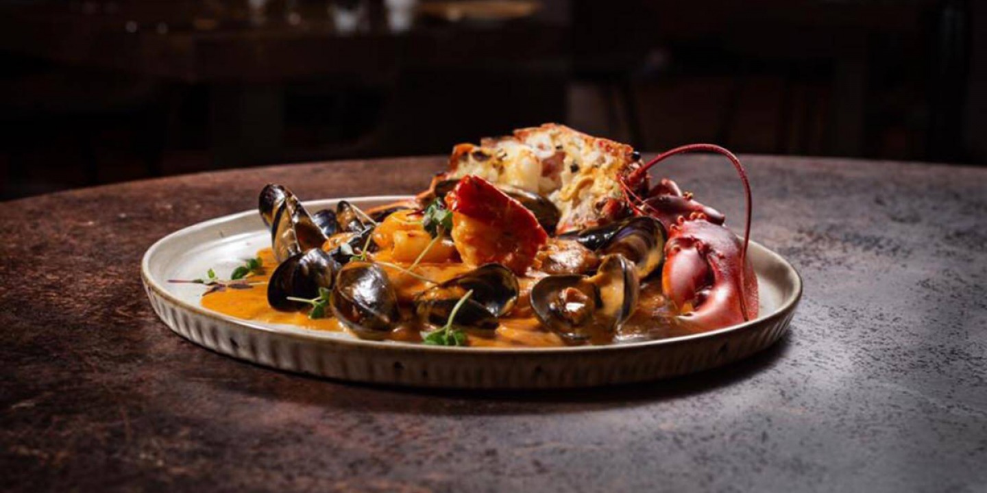 Mussels, lobster and crusty bread on a plate of butter sauce