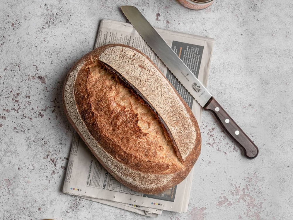 loaf of bread sitting on newspaper with knife
