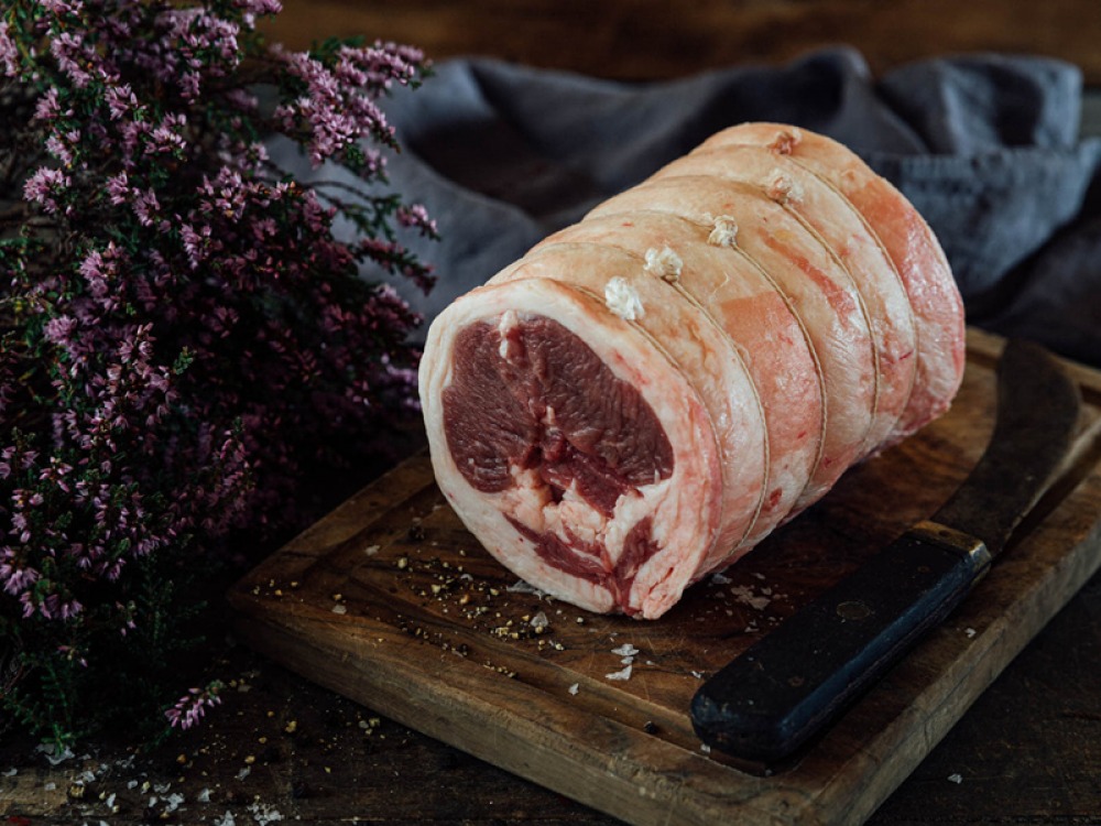 Rolled raw lamb on chopping board with heather
