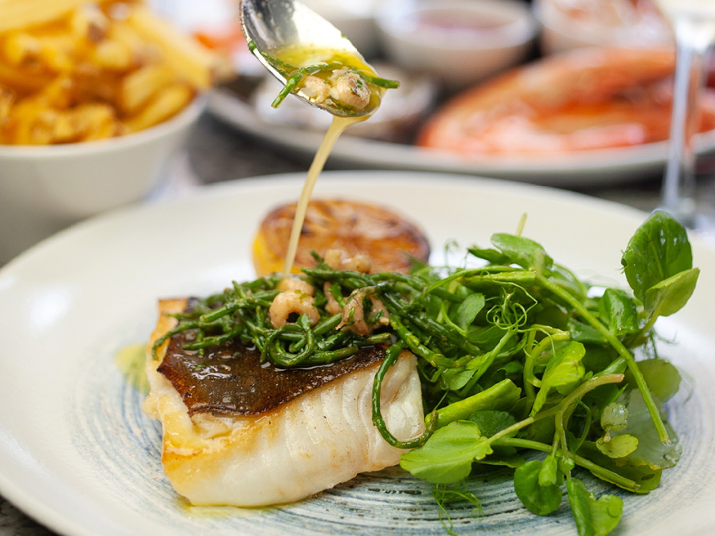 white fish with a butter sauce, lemon and greens