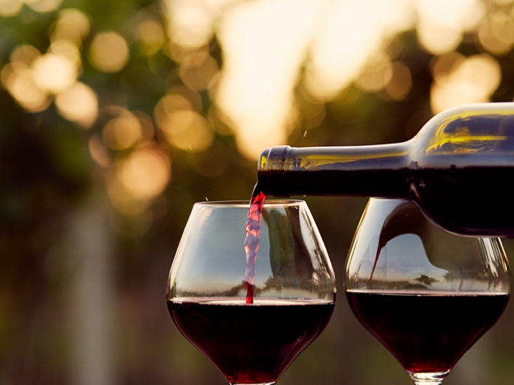 bottle of red wine being poured into glasses