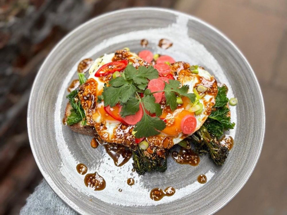 fried egg on toast with dressing, greens and meat