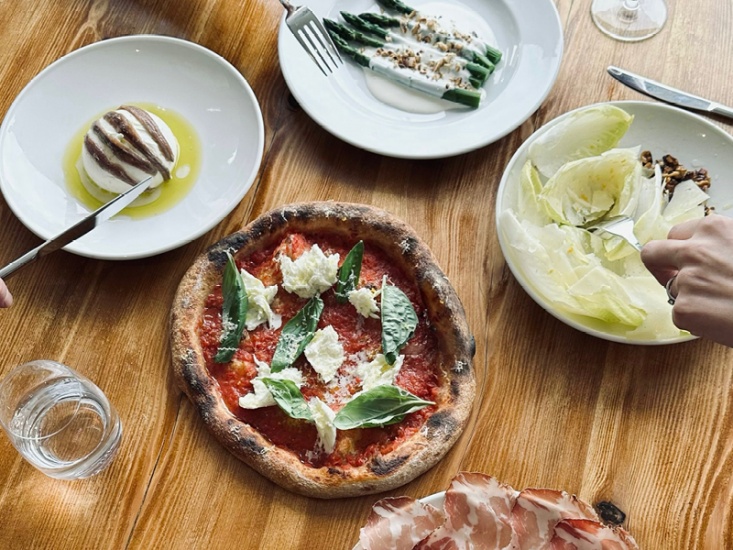 small pizza, cheese and salad on a wooden table