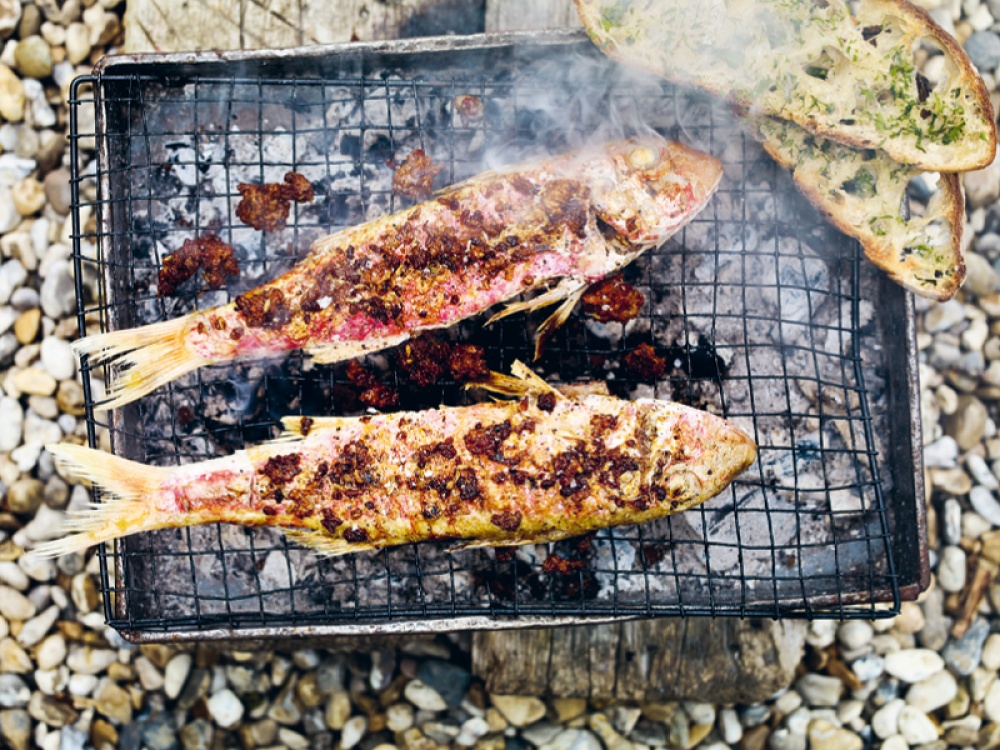 red mullet fish cooking on a make shift barbecue