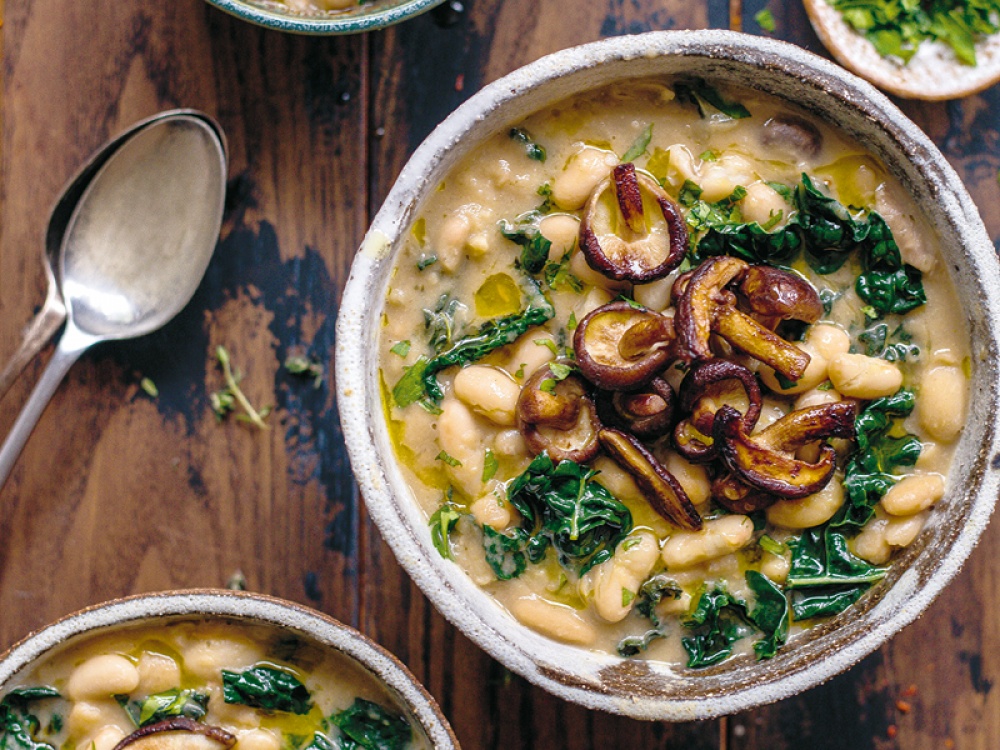 Creamy Cannellini, Mushroom and Cavolo Nero Stew on a dark wooden table