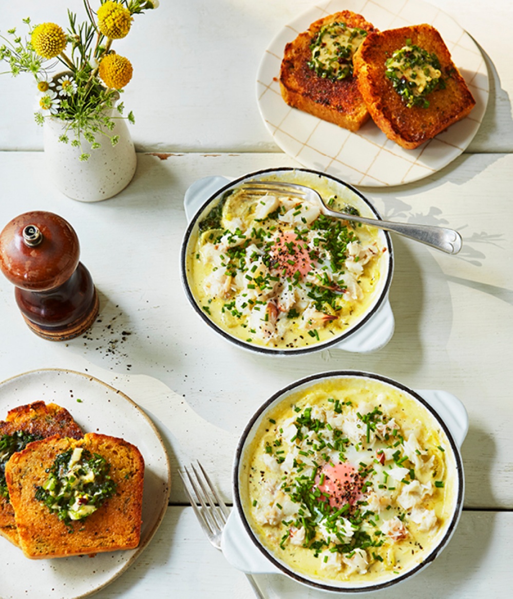 Ariel view of baked eggs in two ramekins with two side plates of corn bread