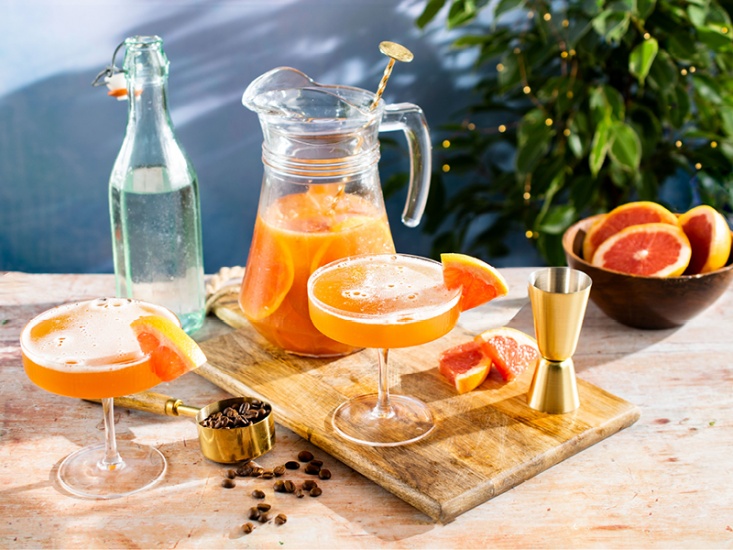 jug of cocktail with 2 cocktails in martini glasses