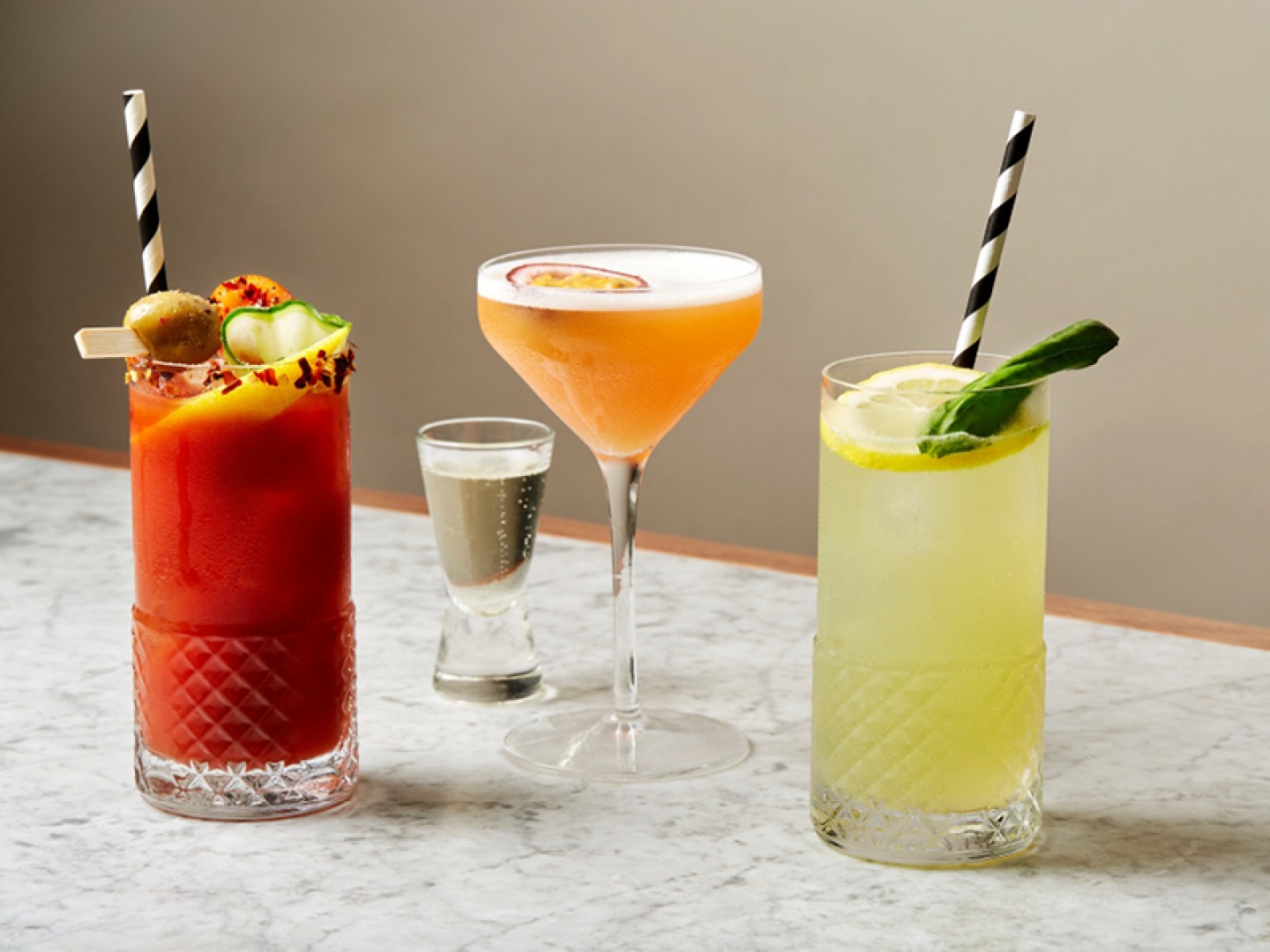 3 different cocktails on a table. Bloody Mary, Pornstar Martini and a Gin Fizz