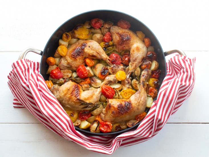 One-Pot Crispy Chicken Legs with Mixed Vegetables in a black pan with a red and white tea towel