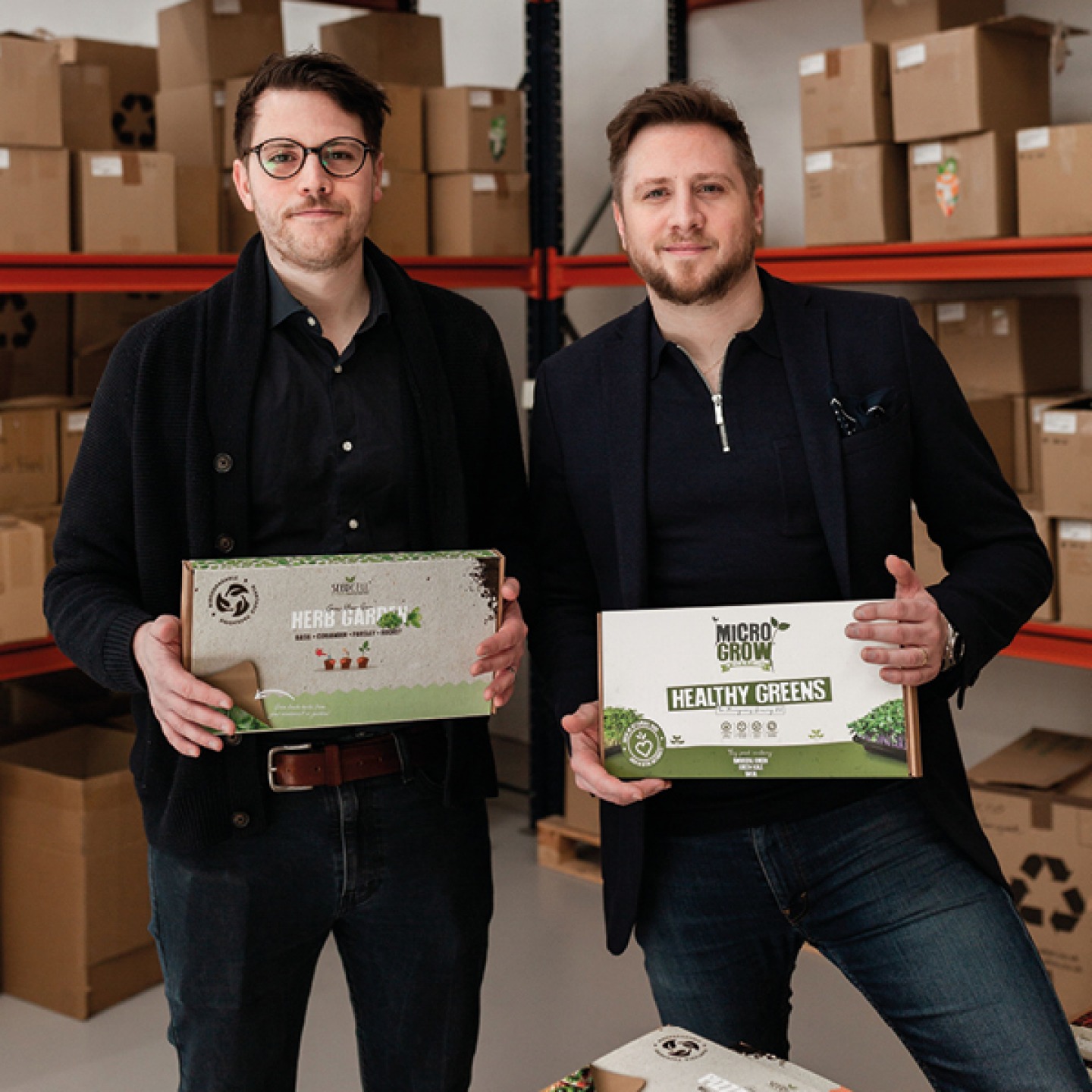 Owner brothers in warehouse holding packed kits