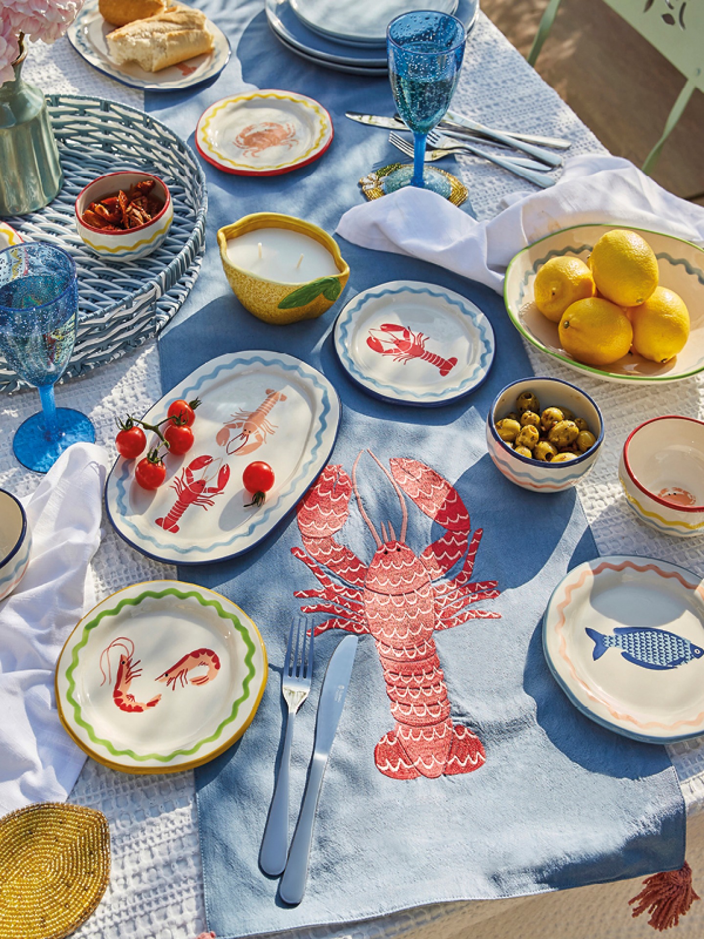 Outdoor Dinner table set with seafood themed dishes and blue, red and yellow colour scheme