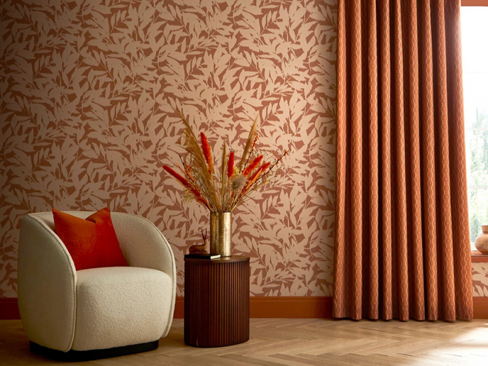 Burnt orange and cream leaf print wallpaper single chair with a cylinder side table and burnt orange curtains