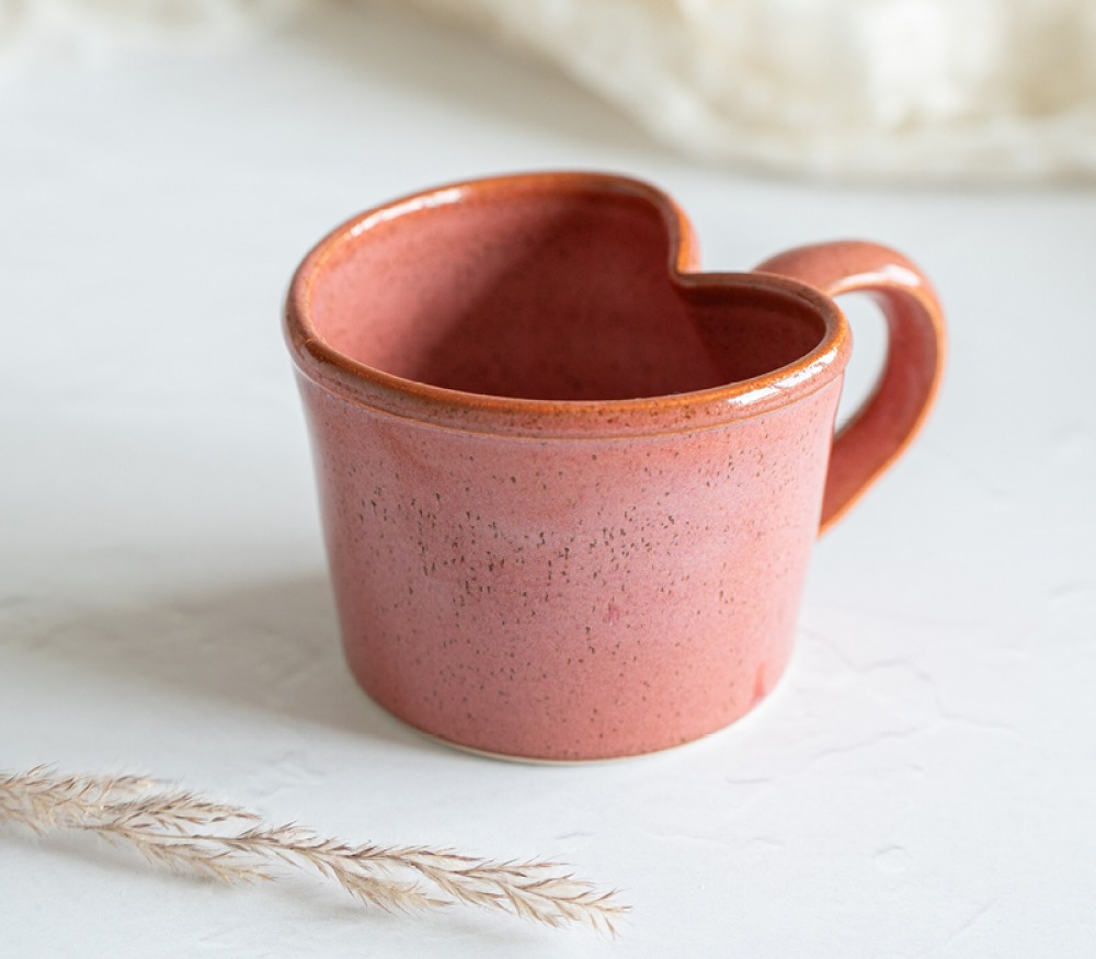 orangey pink drinking mug with a heart shaped top
