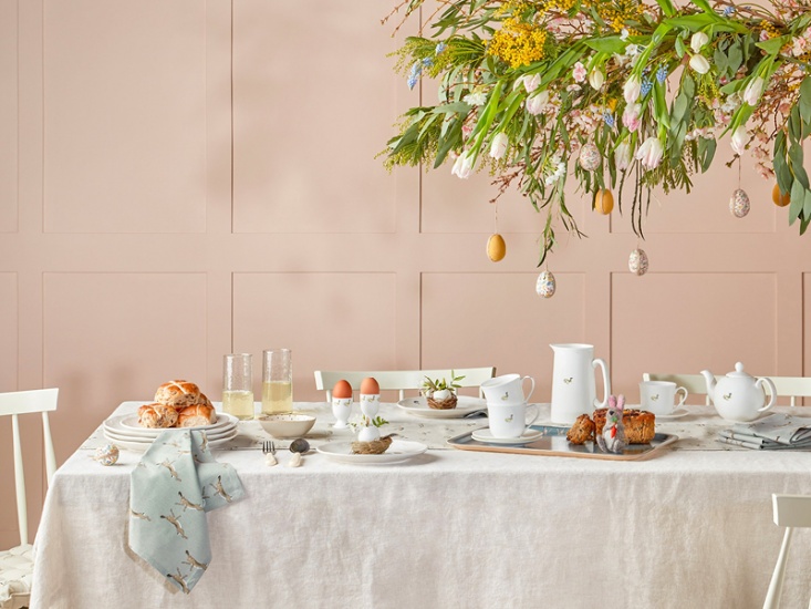 Home table styled for Easter with egg cups, hot crossed buns and floral display