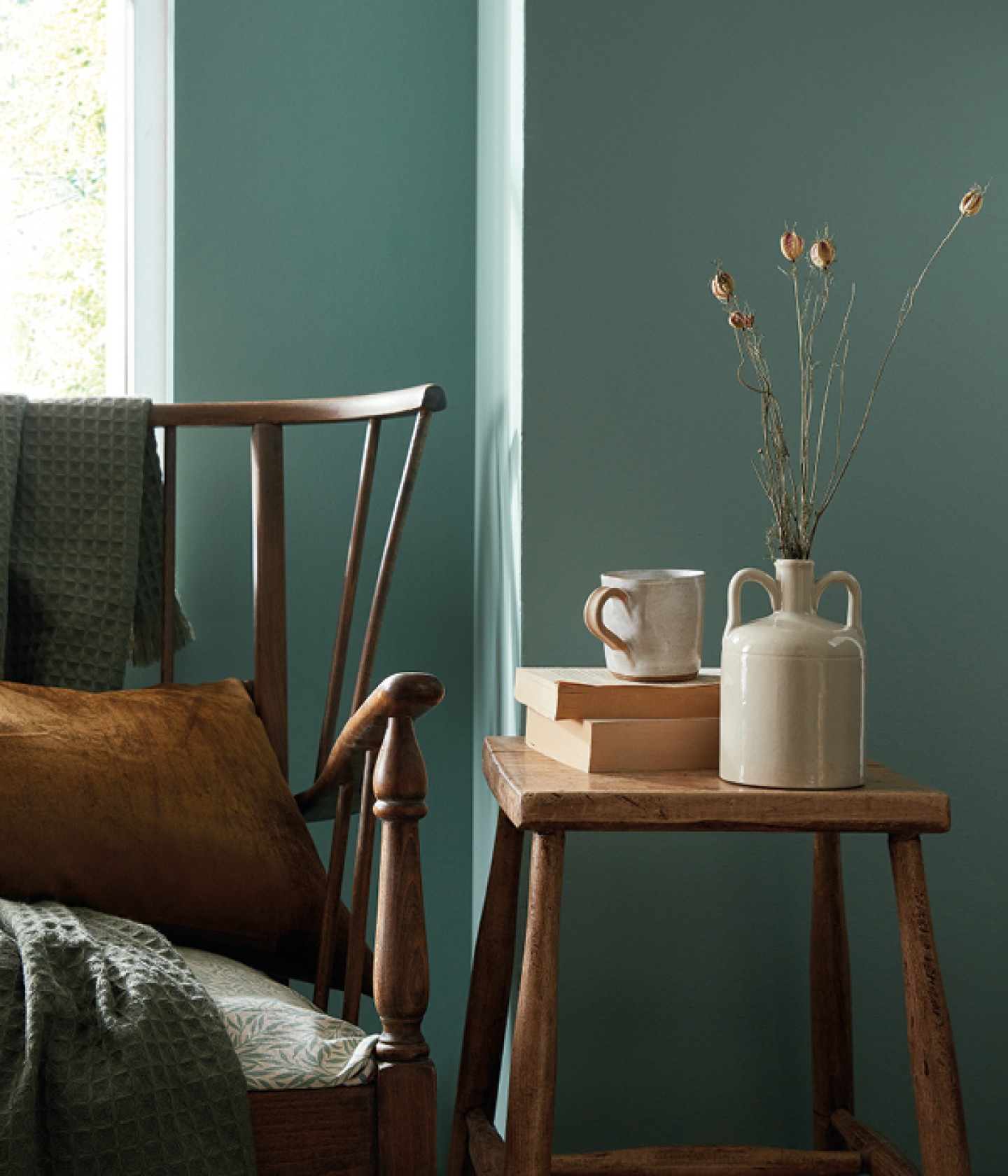 aquamarine wall with wooden stool and rocking chair dressed with cushions and throws