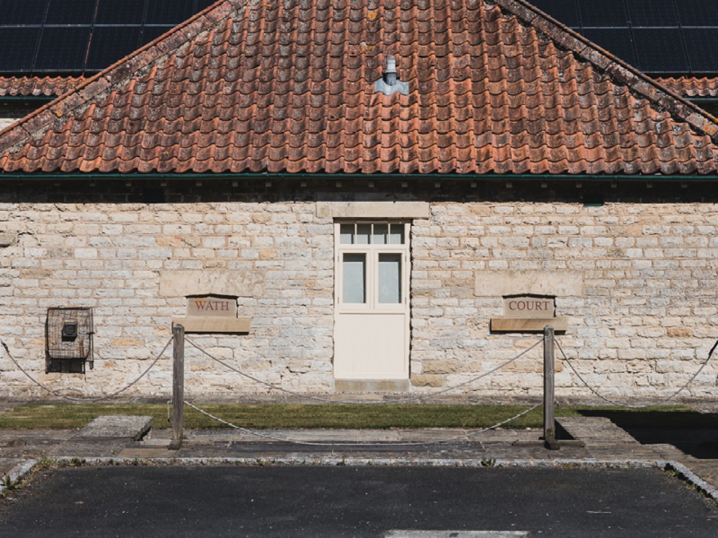stone building with cream door and red roof