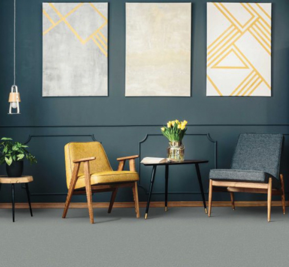 grey flooring with blue panelled wall 1 yellow chair, 1 grey chair and a side table