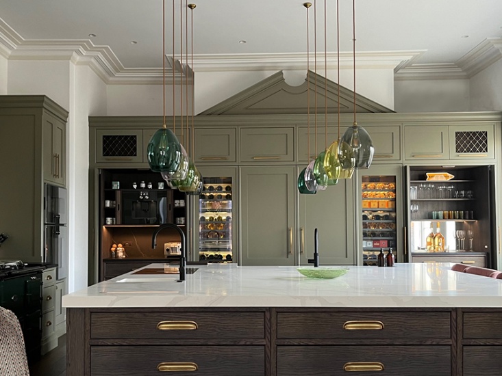 large modern kitchen in sage green with colourful pendant lighting