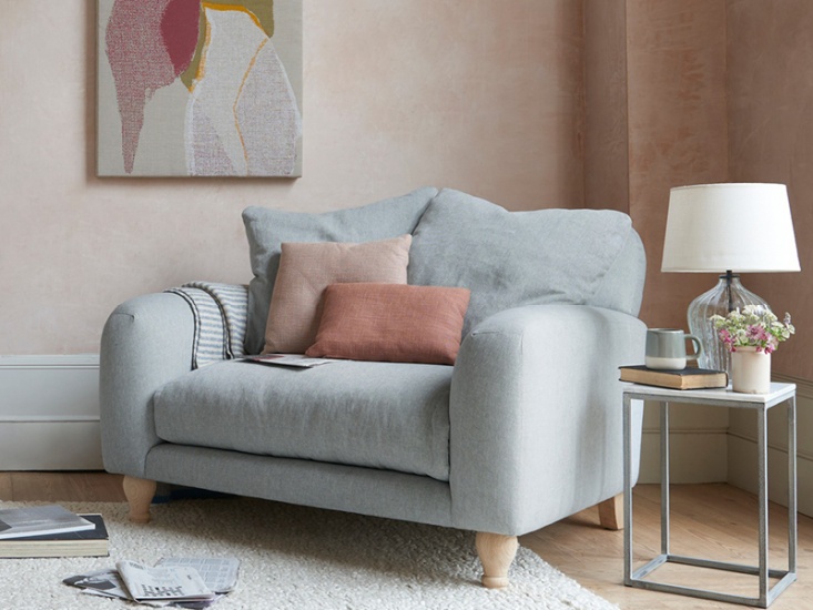 a grey fabric loveseat styled with terracotta cushions