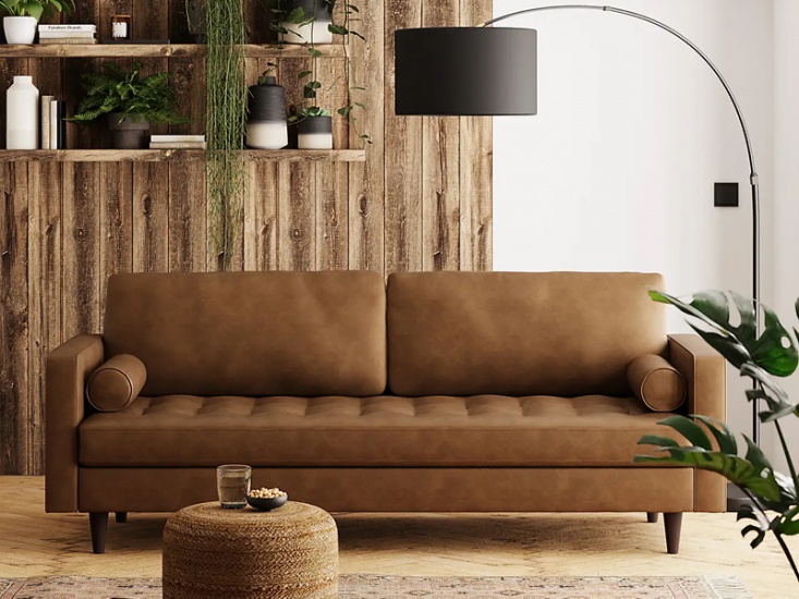Brown leather sofa, plants and books on shelves behind and cantilever style lamp