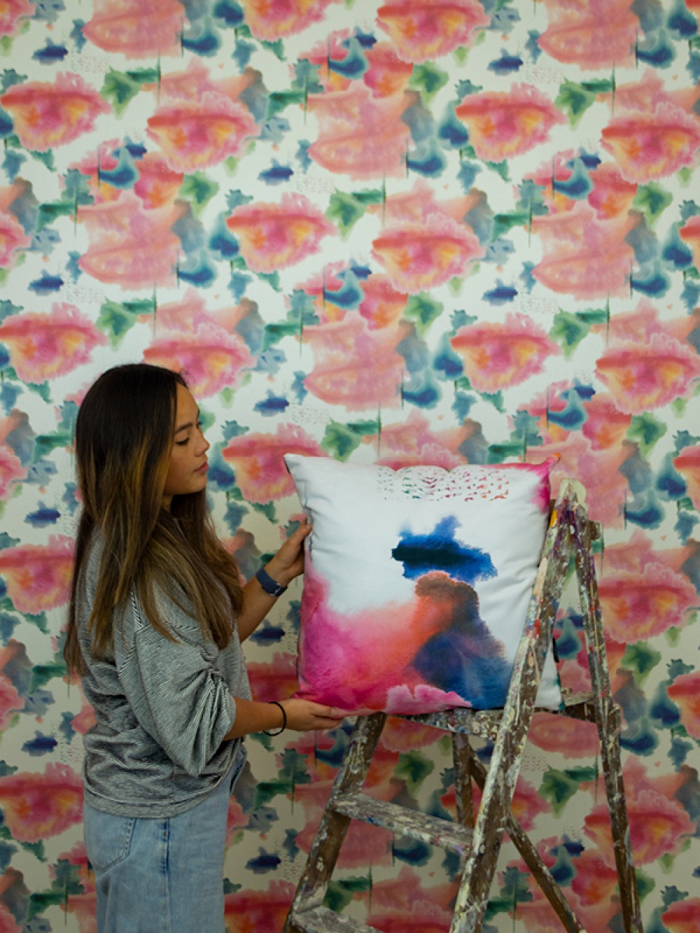 Shiori Naruse standing in front of bold wallpaper holing a printed cushion