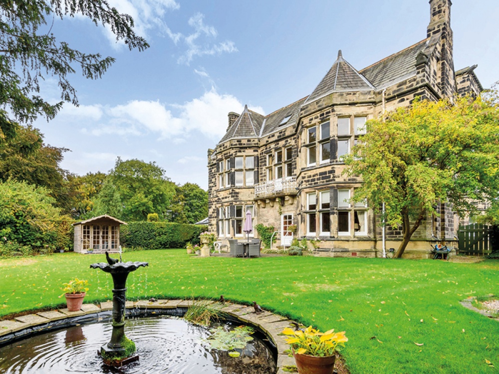 old stone house with a garden and a pond