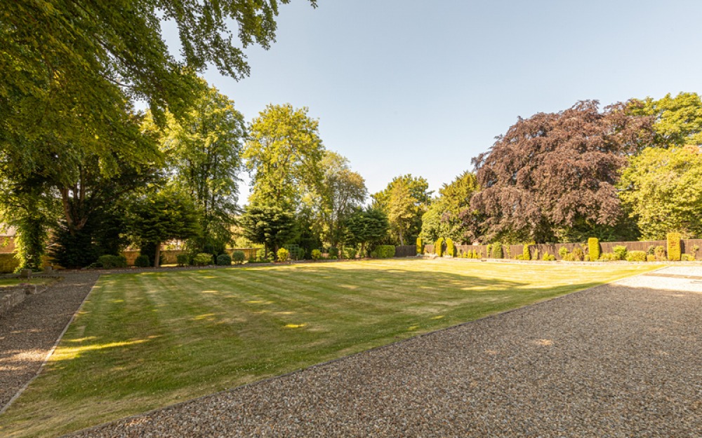Large lawned and gravel garden enclosed by trees
