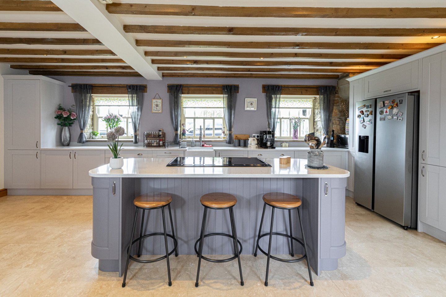 Modern kitchen with lilac island and matching walls, exposed beams