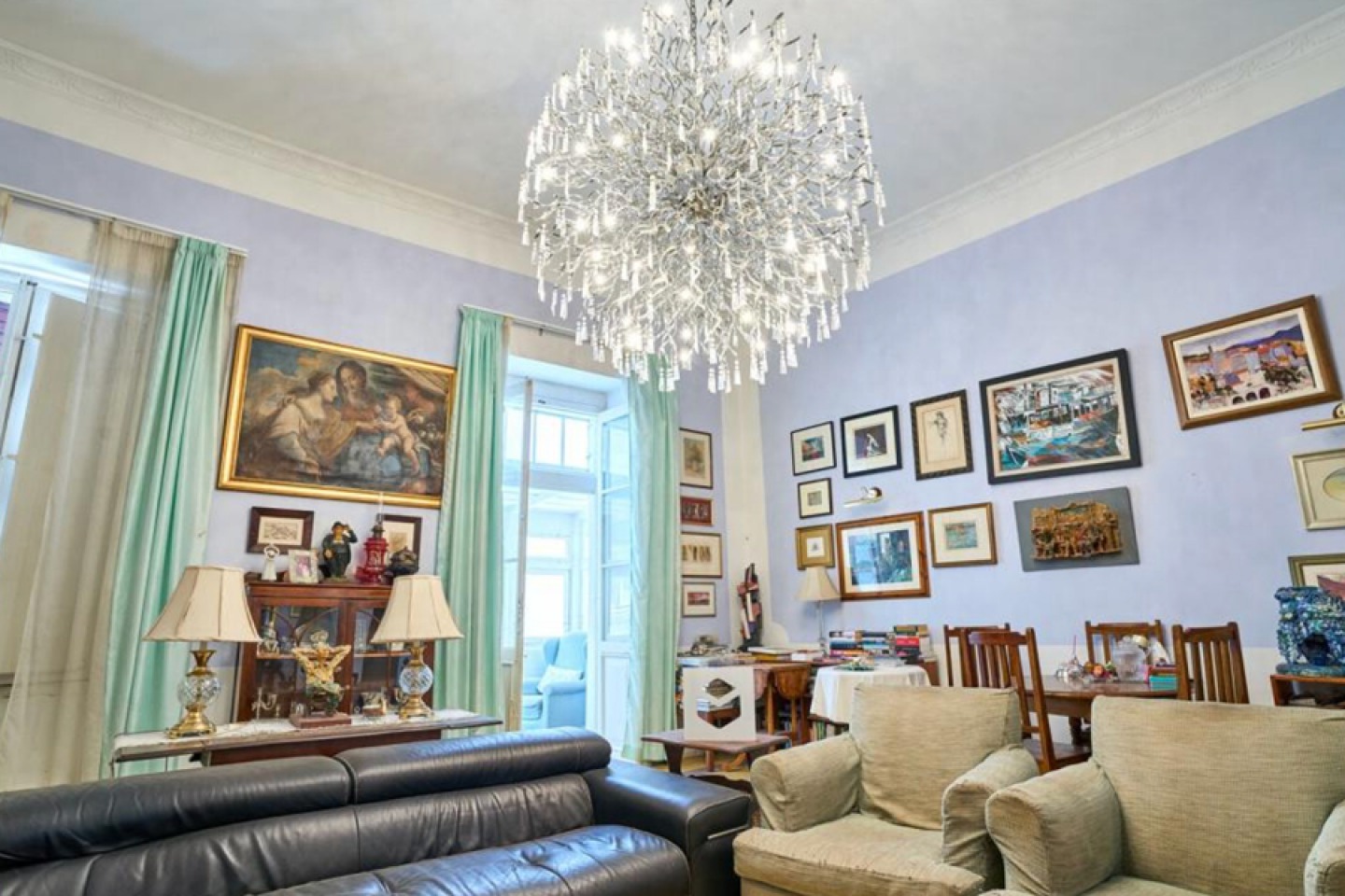 Lilac walled sitting room with mis-matched furniture and large ceiling pendent