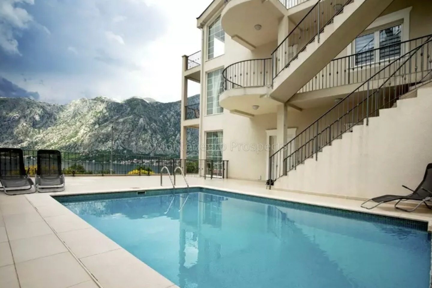 Cream coloured apartment block with private pool overlooking sea and mountains