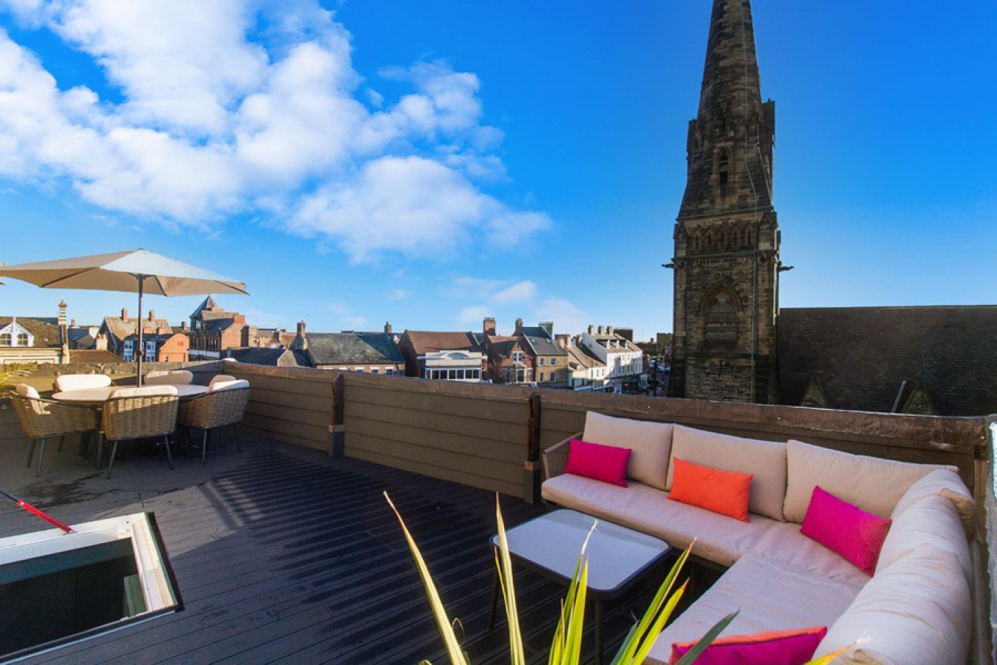 Roof terrace with corner seating, table and chairs set with parasol