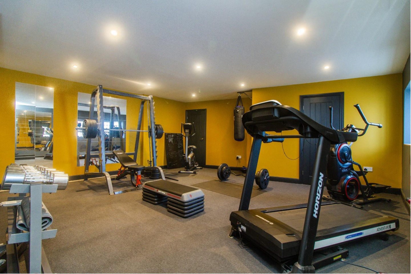 Home gym with yellow walls, mirrors and gym equipment
