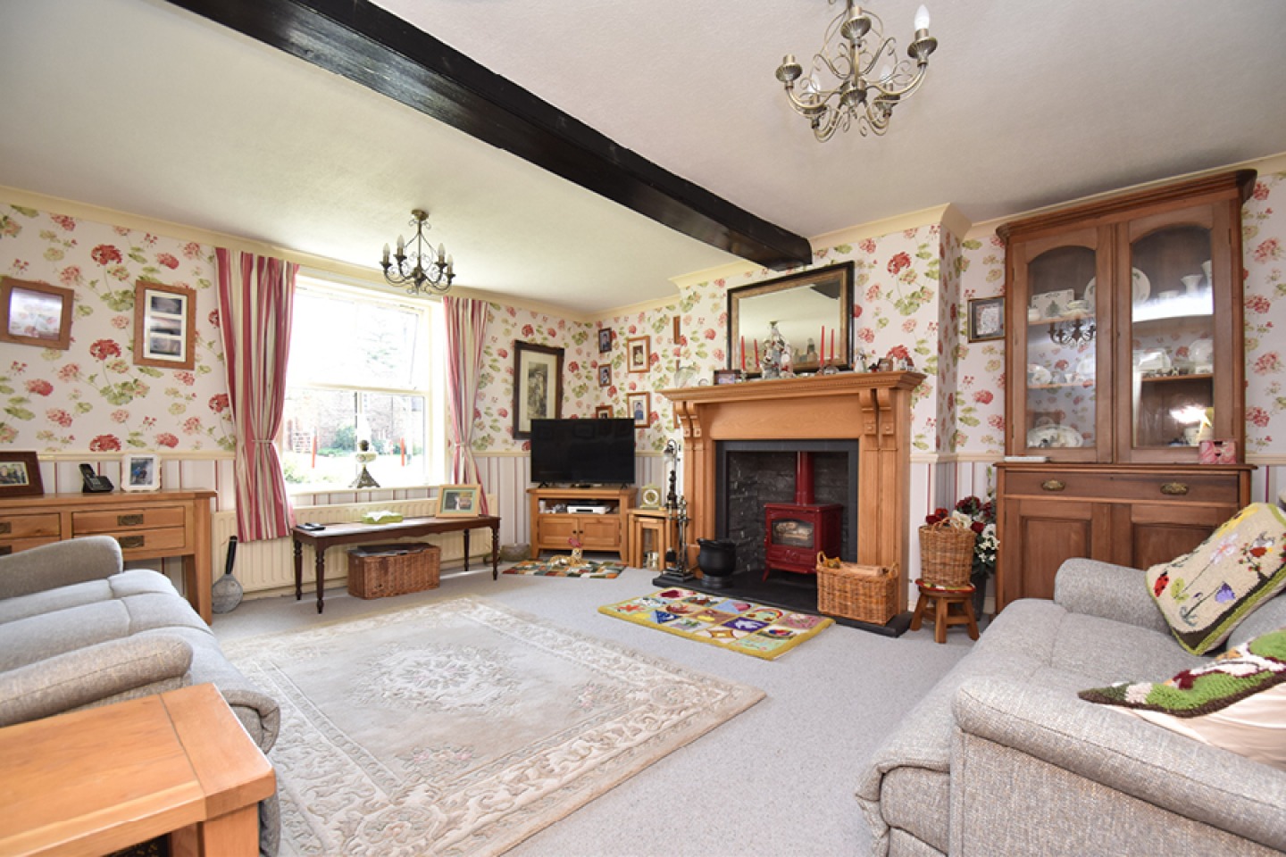 Traditional lounge with floral wall paper and exposed beams
